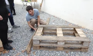 Un animateur finit de monter un carré potager, il est entouré d'adultes