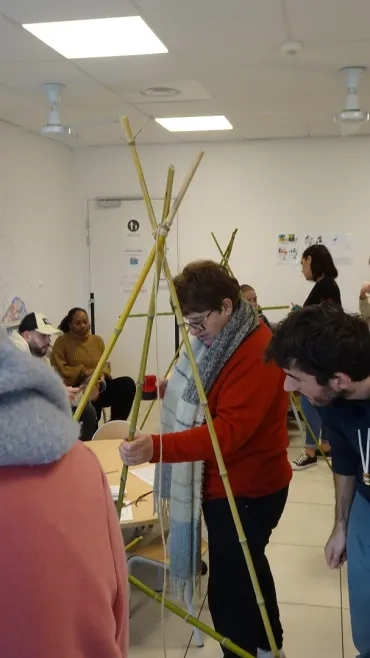 Des adultes construisent un tipi avec des canes de provence