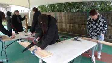 3 adultes scient des planchent de bois