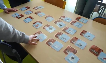 Des cartes d'un jeu pédagogique sur les déchets, éparpillées sur la table 