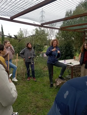 Une animatrice présente un plantoir à un groupe d'adulte dans le jardin