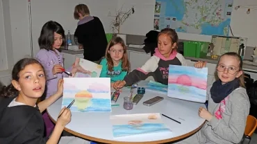 Des enfants montrent leurs dessins de couchers de Soleil