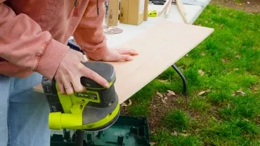 Une adulte ponce une planche de bois