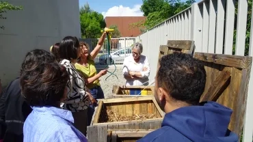 Une animatrice présente un aérateur de compost à un groupe d'adultes