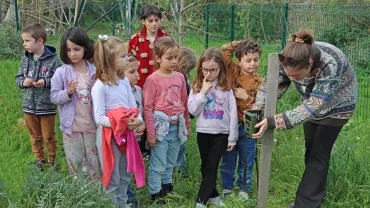 Des enfants regardent leur animatrice accrocher un appareil photo à un pilier