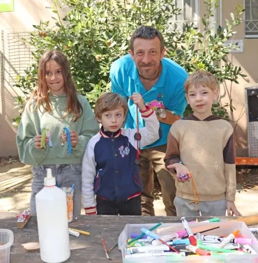 Un groupe d'enfants et leur animateur montrent leurs pendentifs en bois