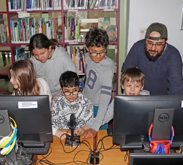 un groupe d'enfants et leur animateur sont devant des ordinateurs avec un microscope
