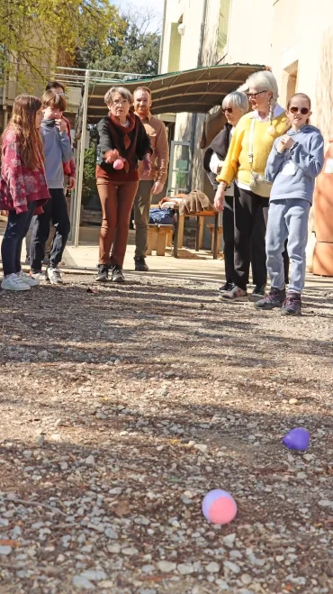 un groupe d'adultes séniors et d'enfants jettent des boules en plastique