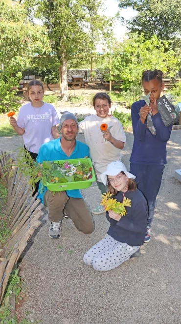 Un groupe d'enfants et leur animateur montrent leur récolte de fleurs et autres feuilles