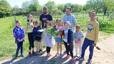 Un groupe d'enfants et leurs animateurs montrent leur récolte de plantes