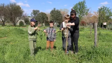 trois enfants et leur animatrice déterrent des poireaux avec une fourche