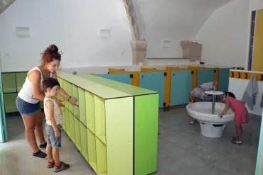 Une animatrice et un enfant sont devant des casiers dans des sanitaires pour les enfants de maternelles