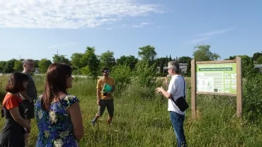Un animateur présente à un groupe d'adultes un aménagement naturel devant un tableau de présentation 