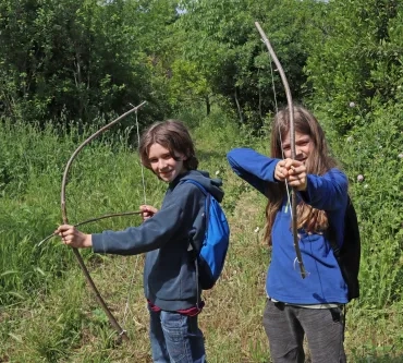 deux enfants font face à l'objectif en bandant des arcs
