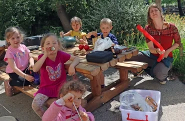 un groupe d'enfants et leur animatrice montrent des instruments de musique