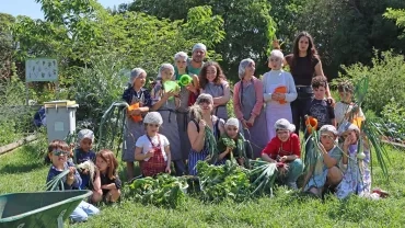un groupe d'enfants et leurs animateurs posent avec des légumes du potager