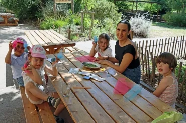 un groupe d'enfants et leur animatrice mettent des plantes dans des porceaux de tissu