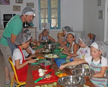 Un groupe d'enfants et leur animateur sont en train de découper des légumes en cuisine