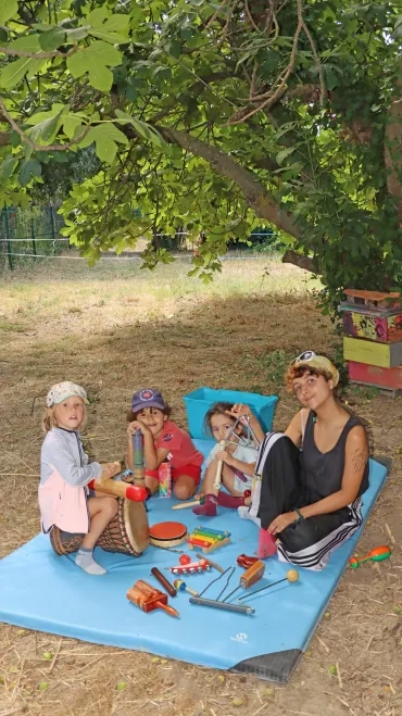 un groupe d'enfants et leur animatrice jouent avec des instruments de musique 
