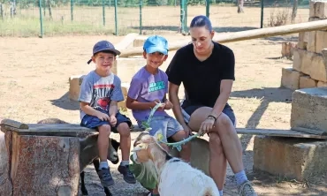 Deux enfants et leur animatrice donnent du chou à une chèvre