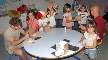 Un groupe d'enfants et leurs animateurs montrent des morceaux de carton avec de l'aluminium