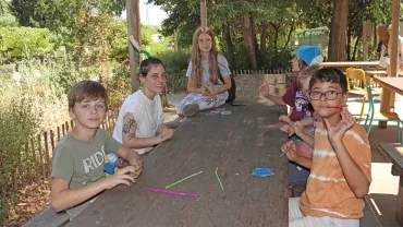 Un groupe d'enfants et leur animatrice déguisée en dinosaure manipulent des cartes