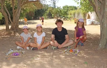 un groupe d'enfants et leur animateur posent avec leurs créations en éléments naturels