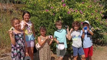 Un groupe d'enfants pose en extérieur avec leurs appareils photos