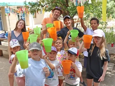 un groupe d'enfants et leur animateur montrent des pichets remplis