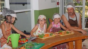 Un groupe d'enfants et leur animateur installent des légumes sur un plateau