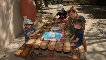 Une animatrice avec quatre enfants regardent des photos pour retrouver la bonne expression faciale de l'animal.