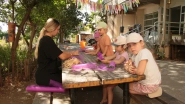 Une animatrice et cinq enfants assis entrain d'emballer des sachets senteurs