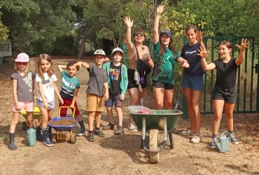 Un groupe d'enfants et leur animatrice jettent des boulettes de boue