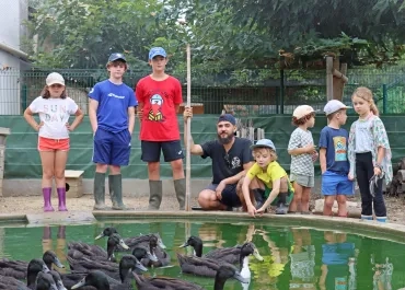 Un groupe d'enfants et leur animateur sont autour de la mare avec les canards à l'intérieur