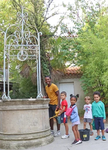 Un groupe d'enfants et leur animateur sont à côté d'un puits