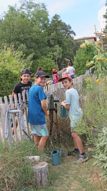 Trois enfants posent avec une pompe à main