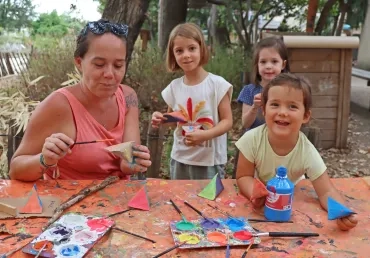 Un groupe d'enfant et une animatrice montrent des maracas colorées