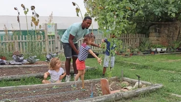Un groupe d'enfants et un animateur posent des cosses au pieds des plantations