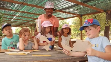 Un groupe d'enfants et leur animatrice font un puzzle géant sur une table