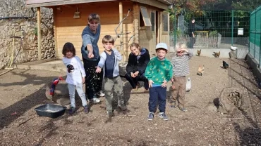 un groupe d'enfants et leurs animateurs jettent du grain aux poules