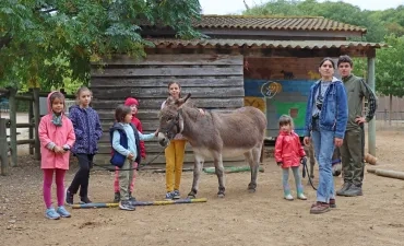 un groupe d'enfants et leur animatrice posent avec deux ânes