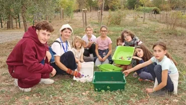 un groupe d'enfants et leurs animateurs posent dans l'herbe avec les bacs contenant des fleurs et des feuilles