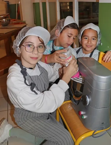 Trois enfants montent des blancs en neige à l'aide d'un robot ménager