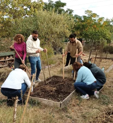 Les participants sont regroupés autour du jardin avec des outils (grelinettes)