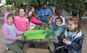 un groupe d'enfants et leur animatrice tordent de l'osier