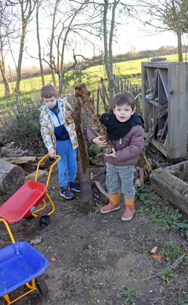 deux enfants soulèvent des bûches de bois