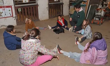 un groupe d'enfants et leur animateur sont assis en rond avec un lapin au centre