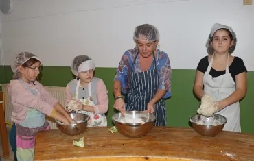 un groupe d'enfants et leur animatrice malaxent un pâte dans des saladiers