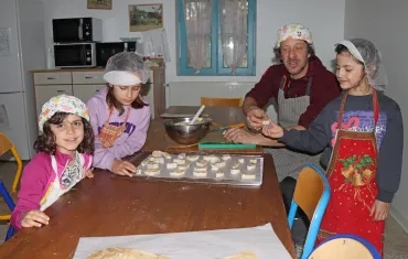 en cuisine, un groupe d'enfants et leur animateur déposent des morceaux de pâte sur des plaques