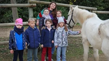 un groupe d'enfants et leur animatrice posent avec un cheval